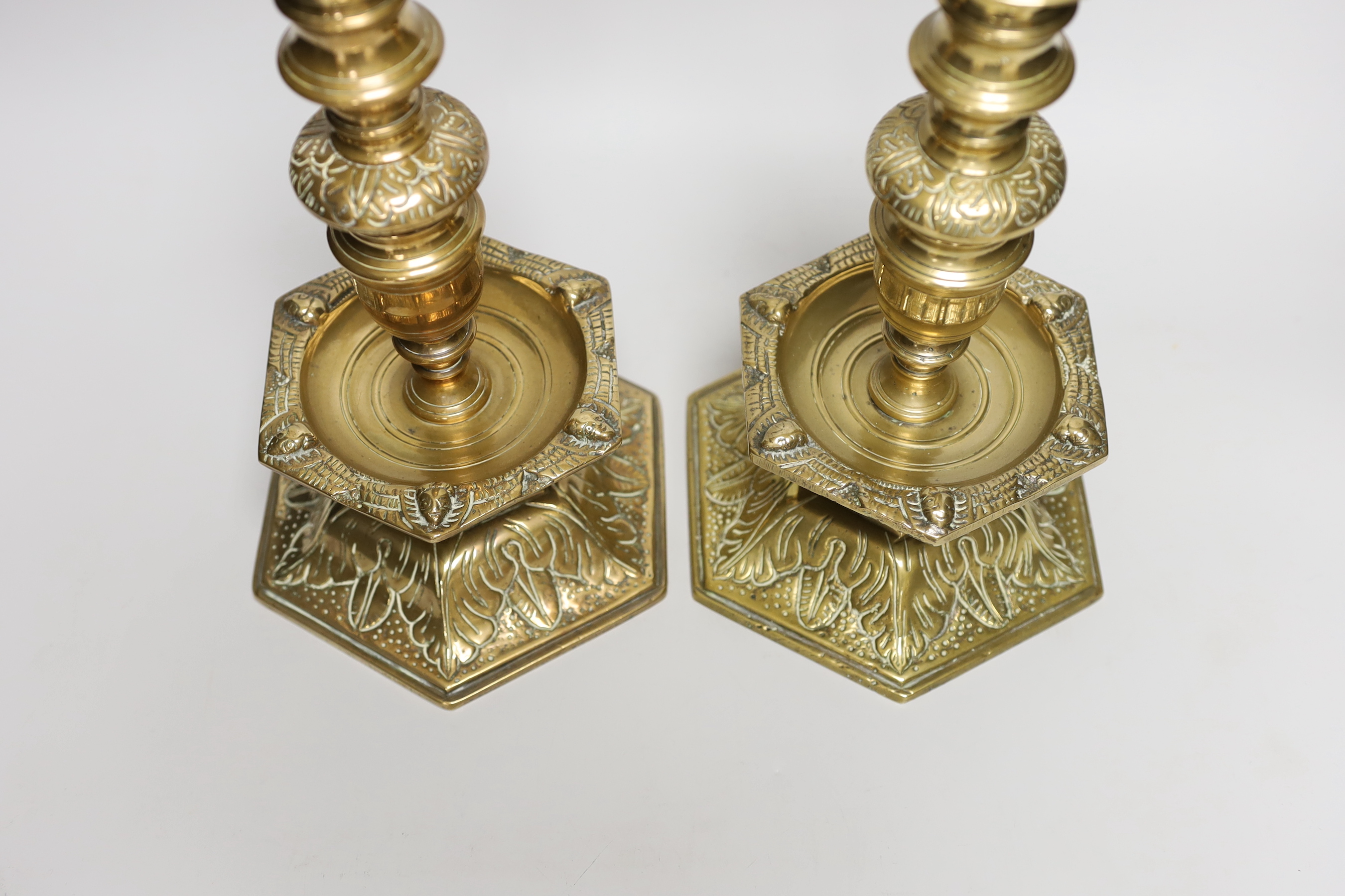 A pair of 19th century Scandinavian candlesticks, each with hexagonal domed bell base cast with acanthus, hexagonal mask cast drip tray and vase knopped stem, 28cm